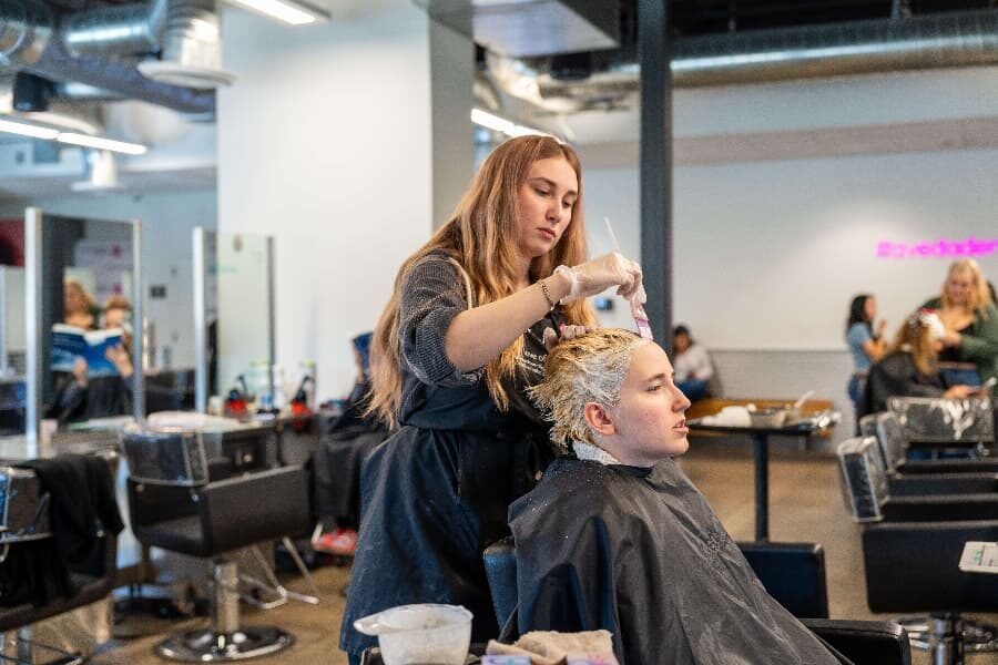 aveda institutes cosmetology student working on clients hair