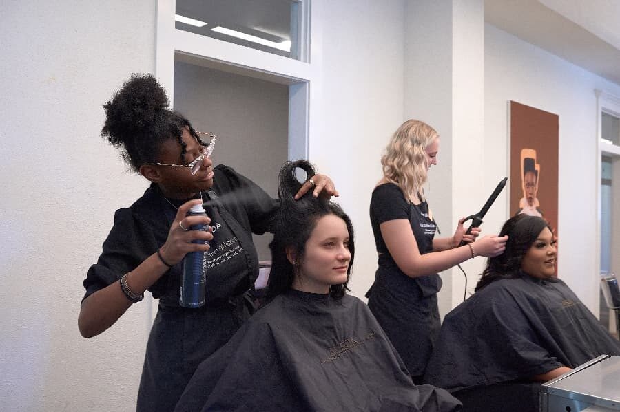 students in cosmetology attire receiving hair services at Aveda Inspire Greatness Institutes